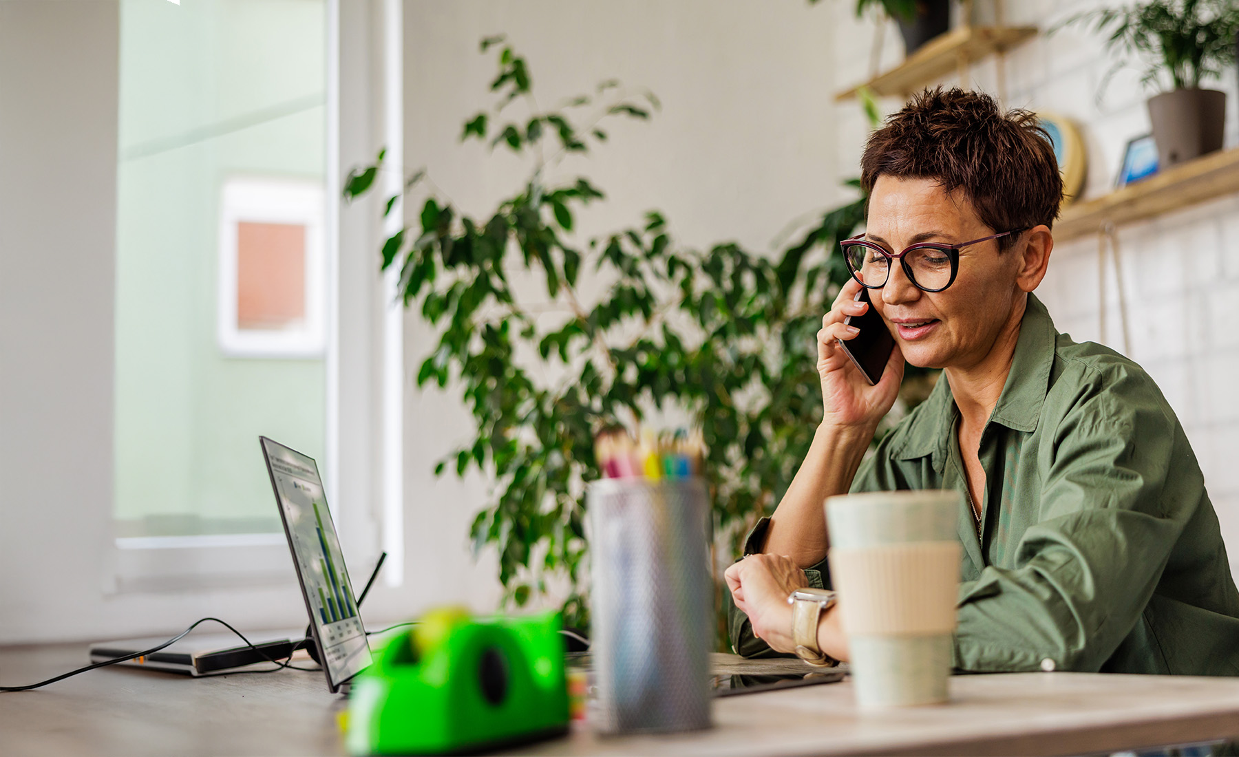 A woman wearing glasses talks on the phone in her office